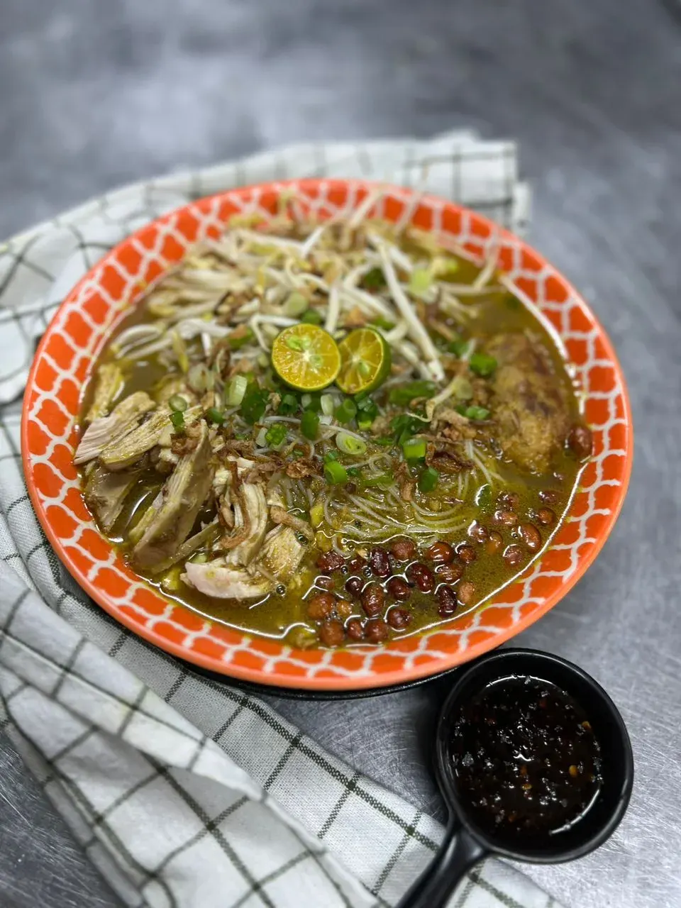 Bowl of bihun soto with shredded chicken and calamansi